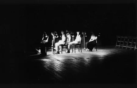 Przestrzeń miejska. Ulica wyglądająca jak tuż po zamieszkach. Pod zasłoniętymi witrynami sklepowymi leżą białe flagi. Nad drzwiami budynki widnieje napis "SEMPRINI".