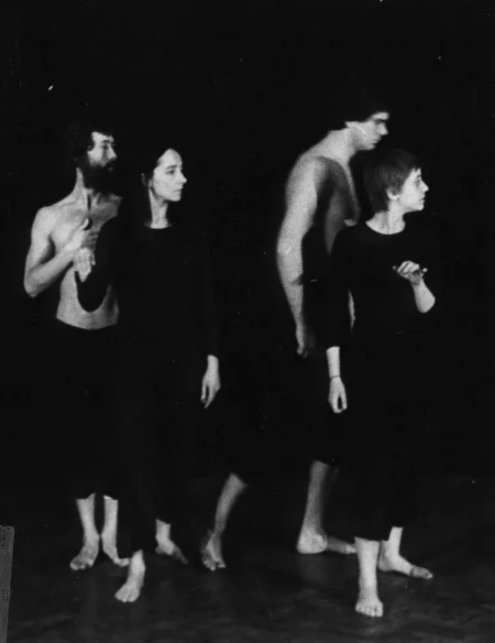 Dwie aktorki i dwóch aktorów. Stoją zwróceni profilem w stronę widza. Aktorzy ubrani są w czarne spodenki i mają nagie torsy. Aktorki ubrane są w czarne spodnie i czarne koszulki. Wszyscy są boso.