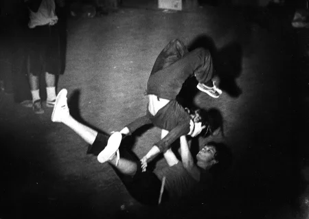 Na podłodze na plecach leży aktor. Ma uniesione nogi. W rękach trzyma aktorkę, która się o niego opiera.