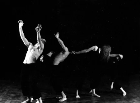 Grupa aktorów i aktorek w szeregu idą w lewą stronę. Wyginają się do tyłu. Dwóch aktorów na początku szeregu wyciąga ręce do góry. Aktorka za nimi ogląda się do tyłu. Aktorzy ubrani są w czarne spodenki i mają nagie torsy. Aktorka ubrana jest w czarne spodenki i czarną podkoszulkę. Wszyscy są boso. Nie widać ich twarzy.