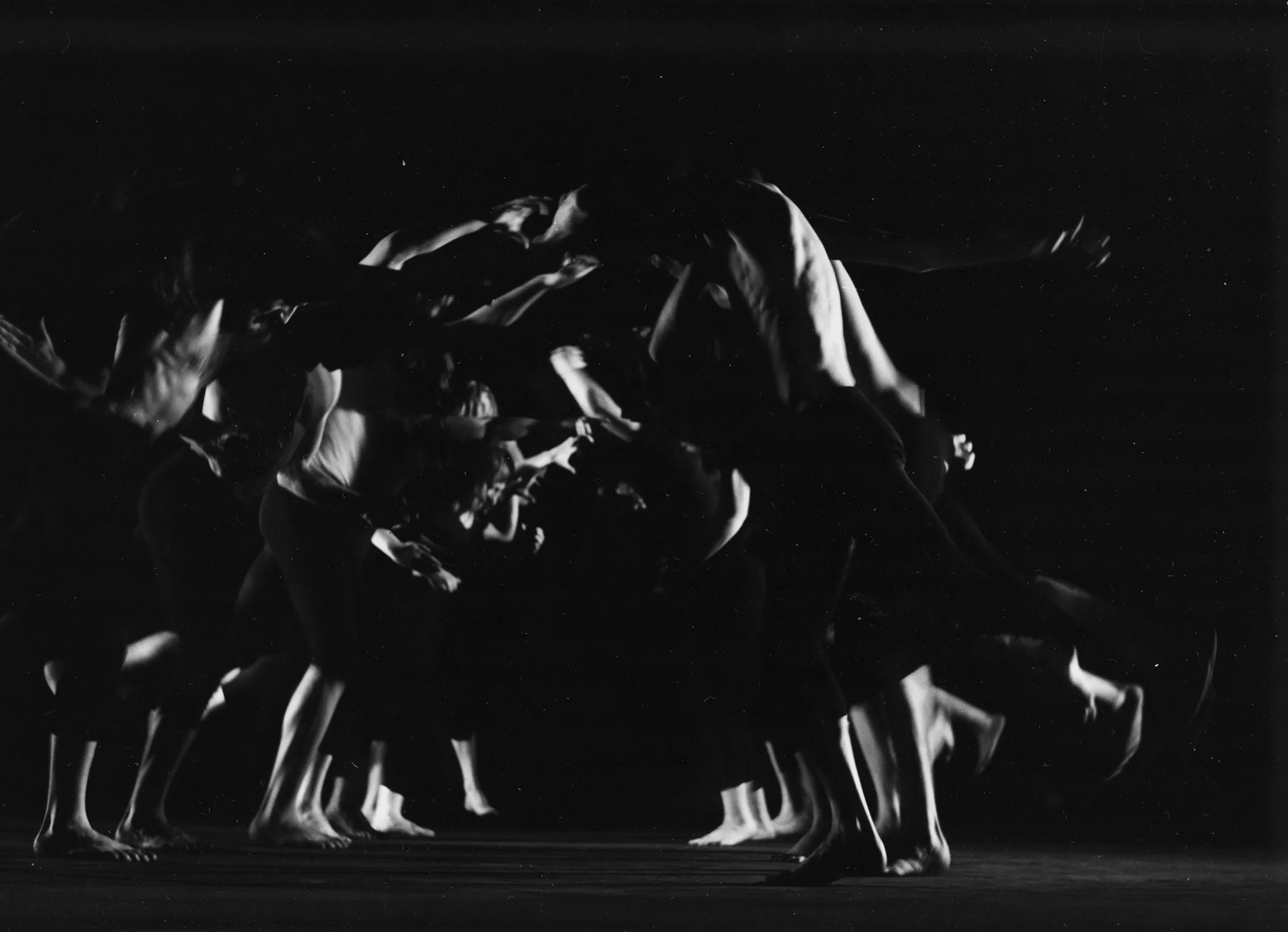 Po lewej i prawej stronie pustej sceny stoją aktorzy zwróceni do siebie twarzami. Są boso, mają czarne krótkie spodenki, niektórzy nie mają koszulek. Wyglądają, jakby chcieli skoczyć w stronę aktorów z drugiej strony sceny.