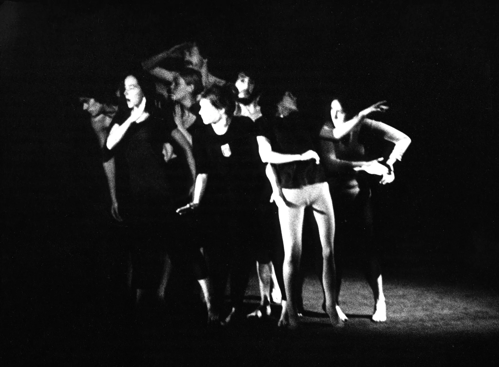 Lekko rozmazane zdjęcie. Aktorzy i aktorki w zwartej grupie. Większość z nich patrzy w lewo ze zdziwieniem. Jedna aktorka, ubrana w czarną podkoszulkę bez spodenek patrzy w prawo.