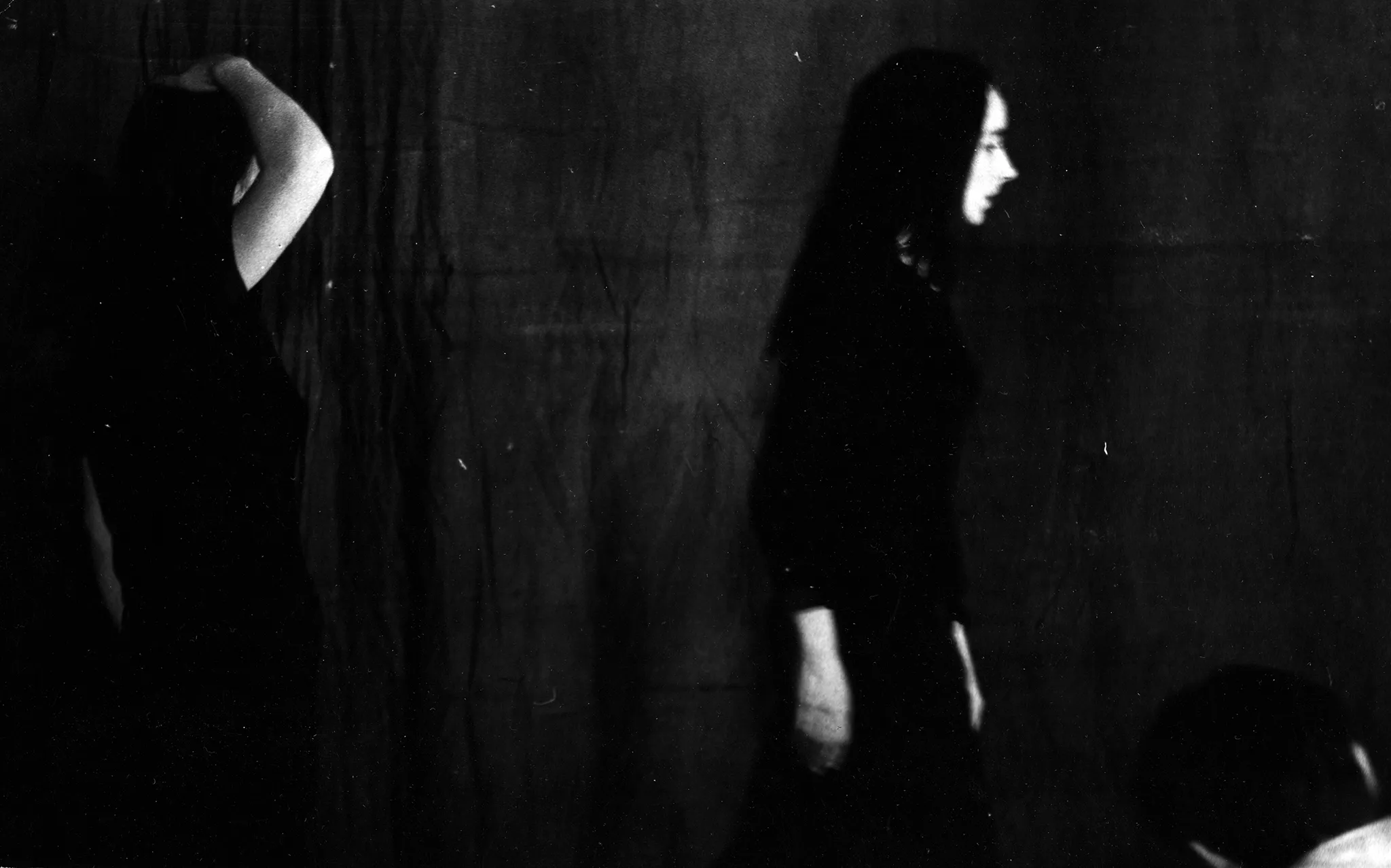 Aktor po lewej stronie ubrany w czarną podkoszulkę ma uniesione do góry ręce. Wygląda, jakby się rozbierał. Po jego prawej stronie aktorka ubrana na czarno, z bardzo ciemnymi dlugimi włosami. Aktorka idzie przed siebie.