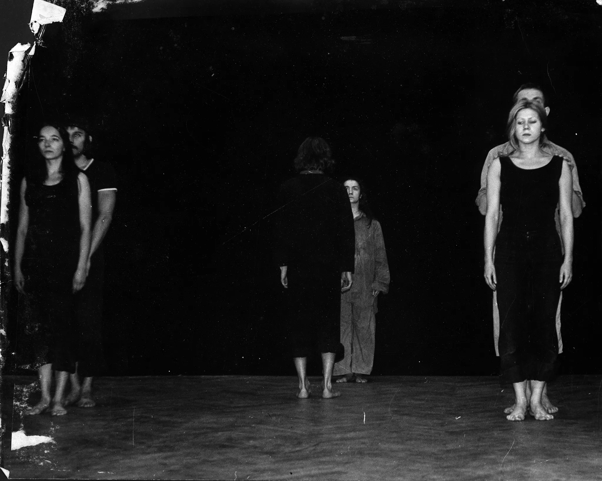 Po lewej stronie zwróceni twarzą do widzów stoją aktor i aktorka. Aktor stoi za plecami aktorki. Aktorka ubrana jest na czarno, aktor za jej plecami ubrany jest w czarną podkoszulkę. Oboje są boso. Po prawej stronie sceny również w ten sam sposób stoją aktor i aktorka. Aktorka ubrana jest tak samo. Aktor ubrany jest w czarną podkoszulkę. W centrum sceny naprzeciwko siebie stoją dwie aktorki. Jedna, bliżej widzów, jest zwrócona do nich plecami. Aktora stojąca bardziej w głębi sceny zwrócona jest do widzów twarzą. Aktorki mają ciemne ubrania. Są boso. Patrzą na siebie nawzajem.