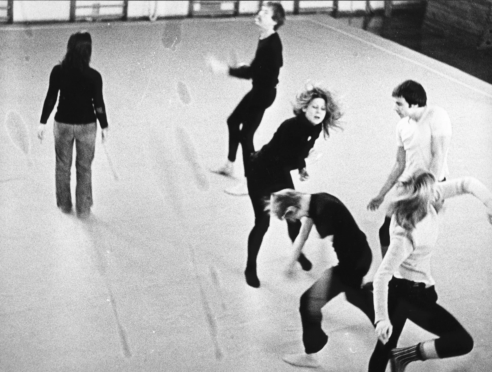 Sześcioro aktorów i aktorek na sali gimnastycznej. Wyglądają, jakby tańczyli. Wszyscy ubrani są w ciemne spodnie. Czworo z nich ubrana jest w czarne koszulki. Pozostała dwójka ubrana jest w białe koszulki.