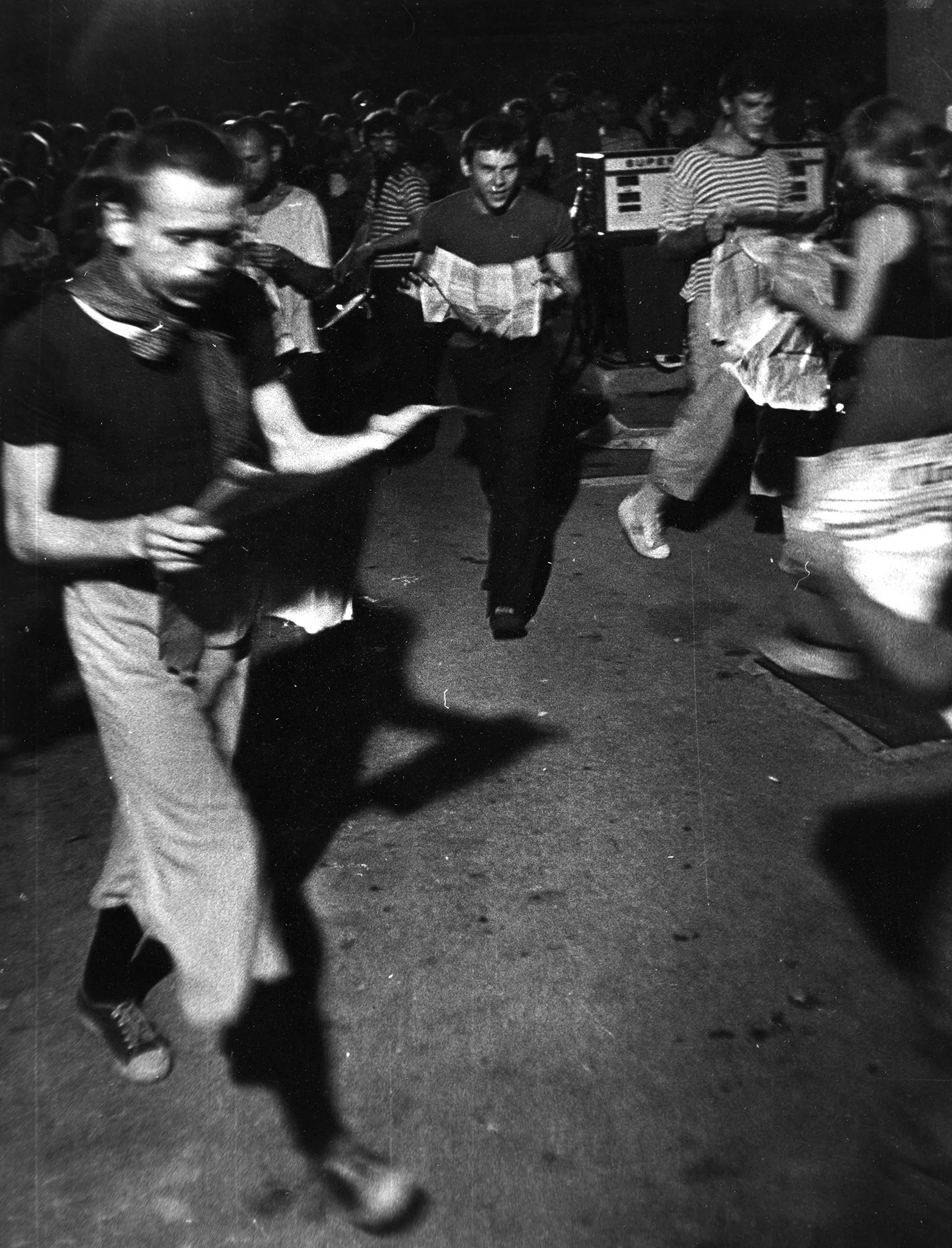 Przestrzeń miejska. Tłum ludzi. Wśród tłumu grupa aktorów i aktorek. Wyglądają, jakby na głos czytali gazety.