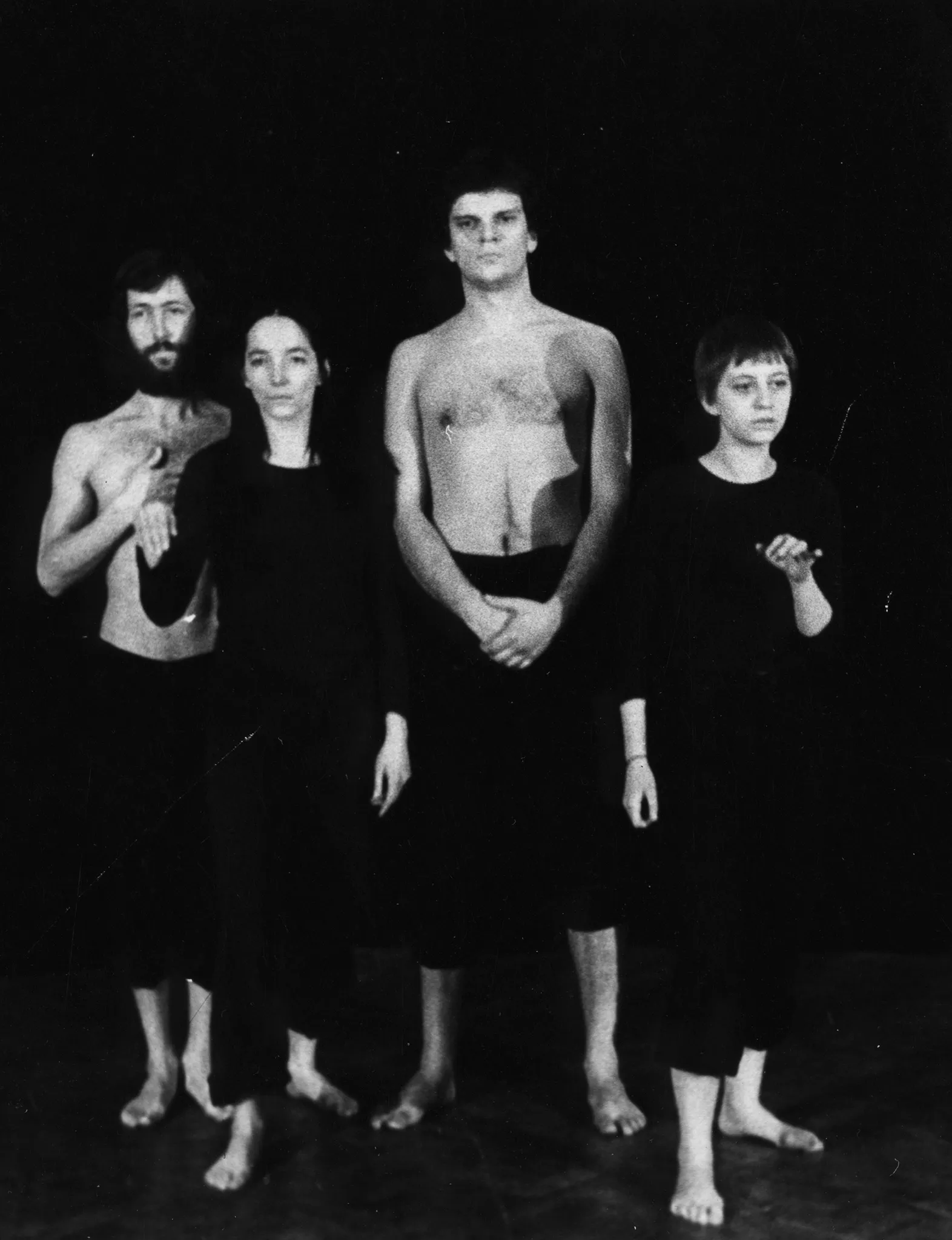 Dwie aktorki i dwóch aktorów. Stoją zwróceni twarzą w stronę widza. Aktorzy ubrani są w czarne spodenki i mają nagie torsy. Aktorki ubrane są w czarne spodnie i czarne koszulki. Wszyscy są boso.