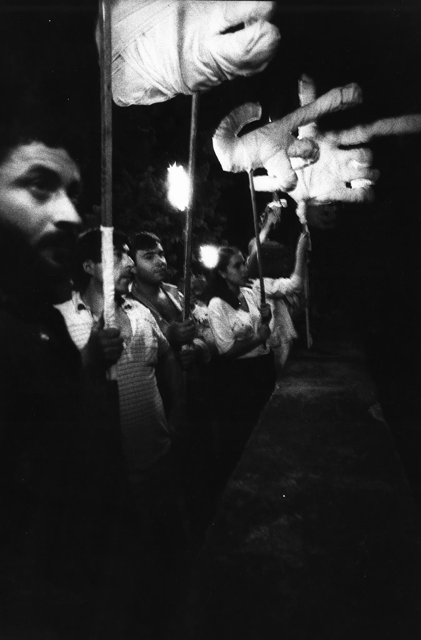 Grupa aktorów i aktorek zwróconych w stronę widza profilem. Niektórzy trzymają w rękach wielkie dłonie na kijach.