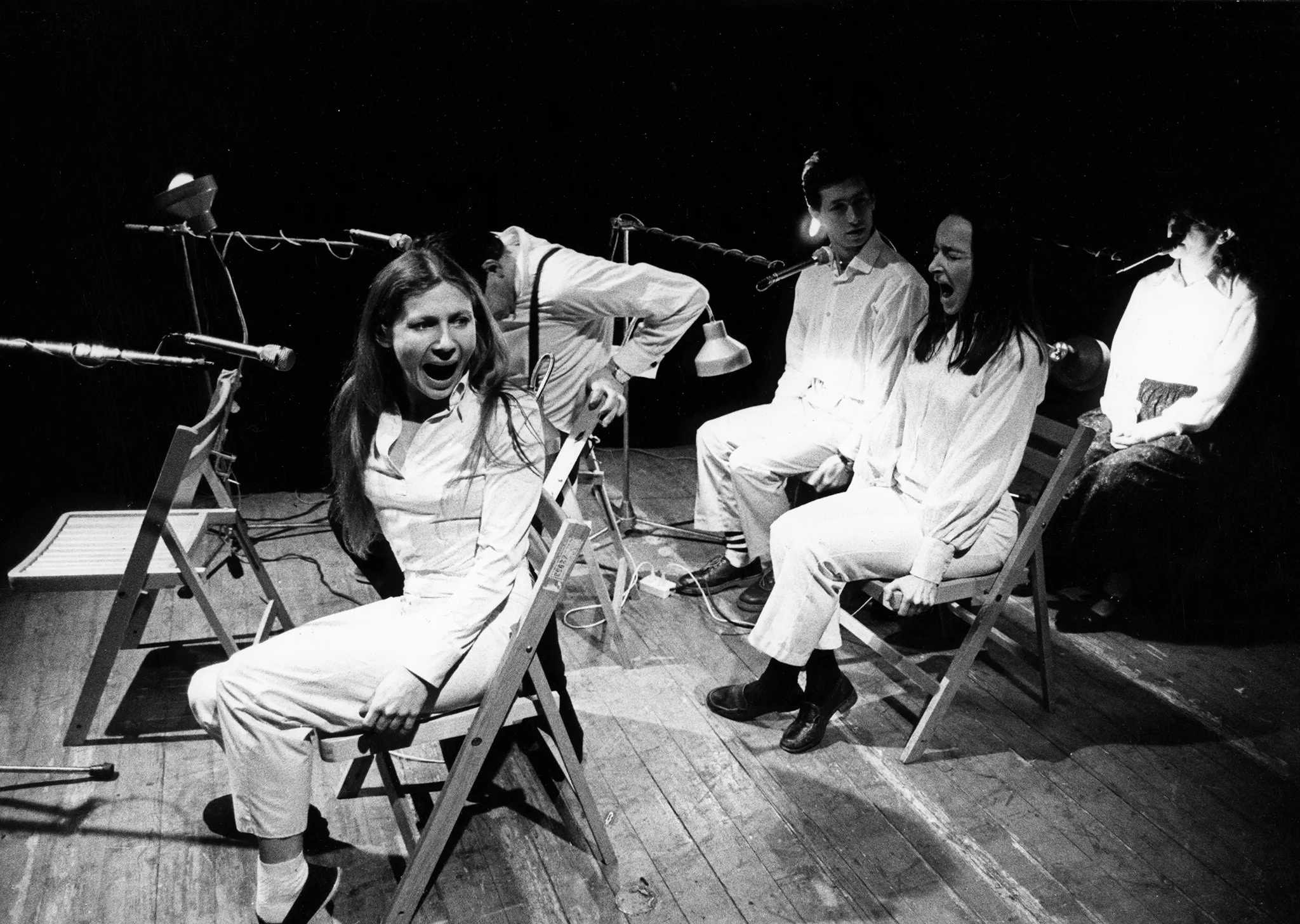 Przestrzeń miejska. Ulica wyglądająca jak tuż po zamieszkach. Pod zasłoniętymi witrynami sklepowymi leżą białe flagi. Nad drzwiami budynki widnieje napis "SEMPRINI". Z prawej strony idzie przechodzień.