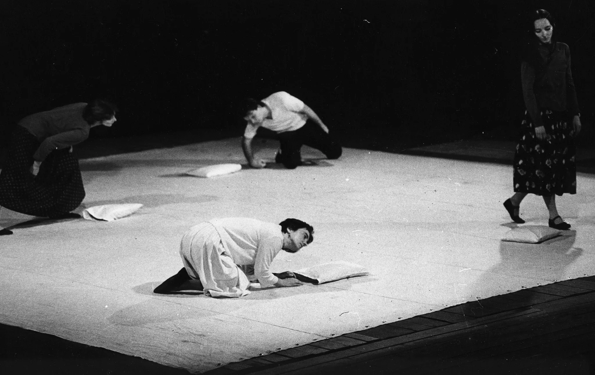 Czteroosobowa grupa aktorów i aktorek na białej płachcie. Troje z nich zamierza położyć się na poduszkach. Jedna aktorka stoi nad poduszką.