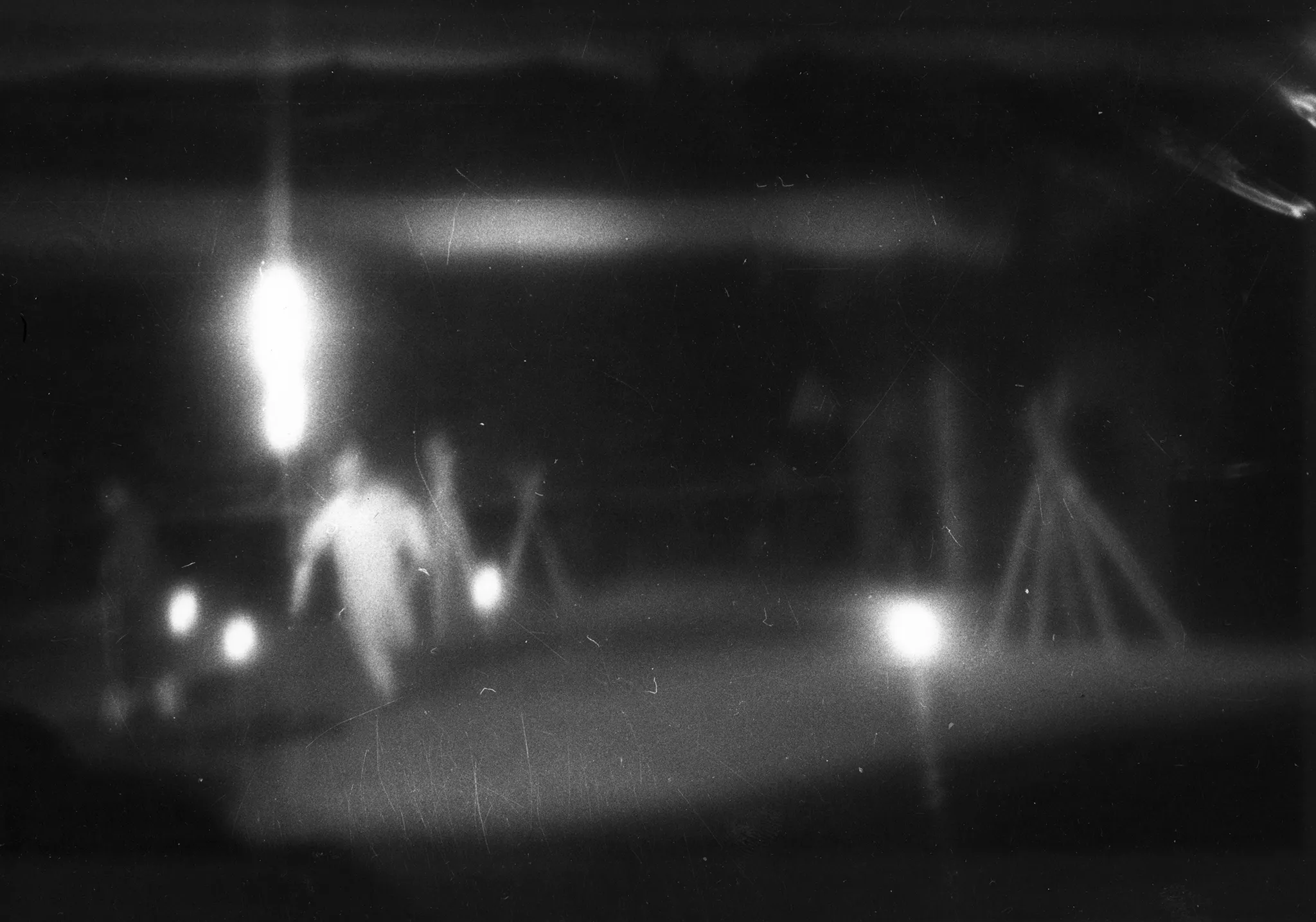 Niewyraźne zdjęcie. W oddali widać biegnącego aktora i kilka świecących reflektorów.